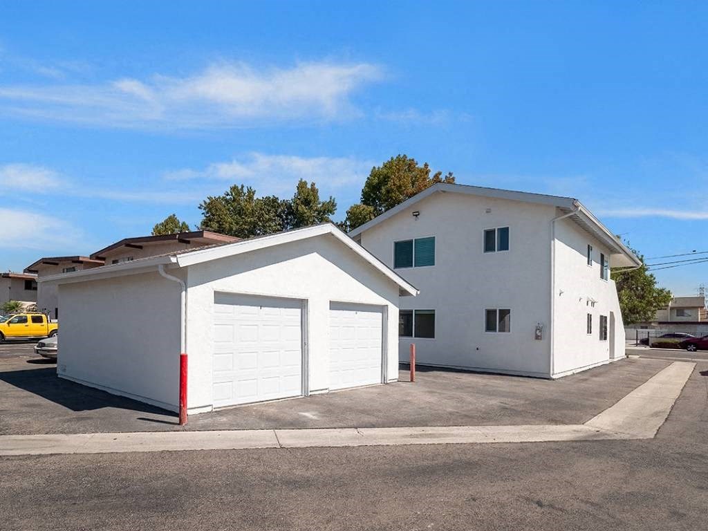 a white building with a white garage and a yellow car in a parking lot