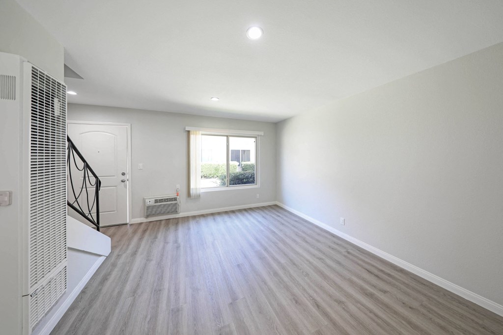 a bedroom with hardwood floors and a large window