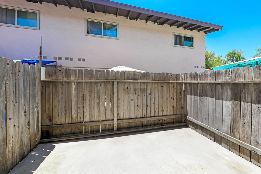 a back yard with a concrete patio and a wooden fence