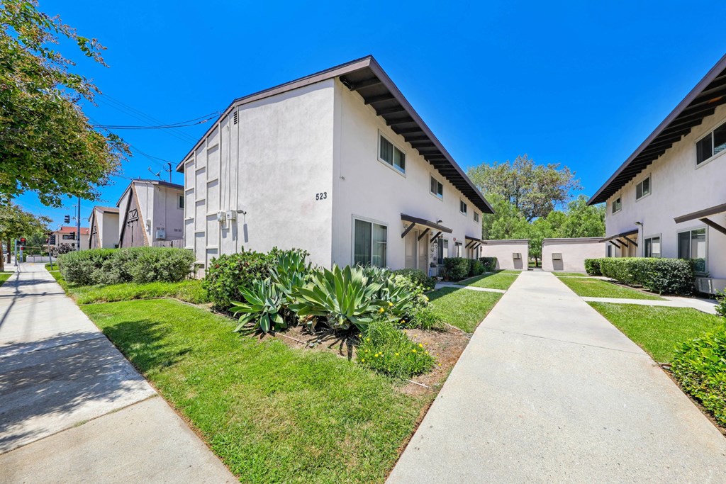 a white building with a black roof and a sidewalk in front of it