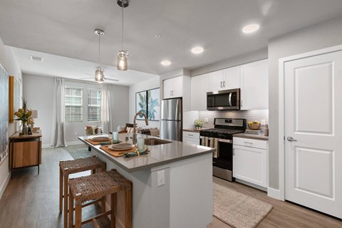 a kitchen with white cabinets and a island with chairs