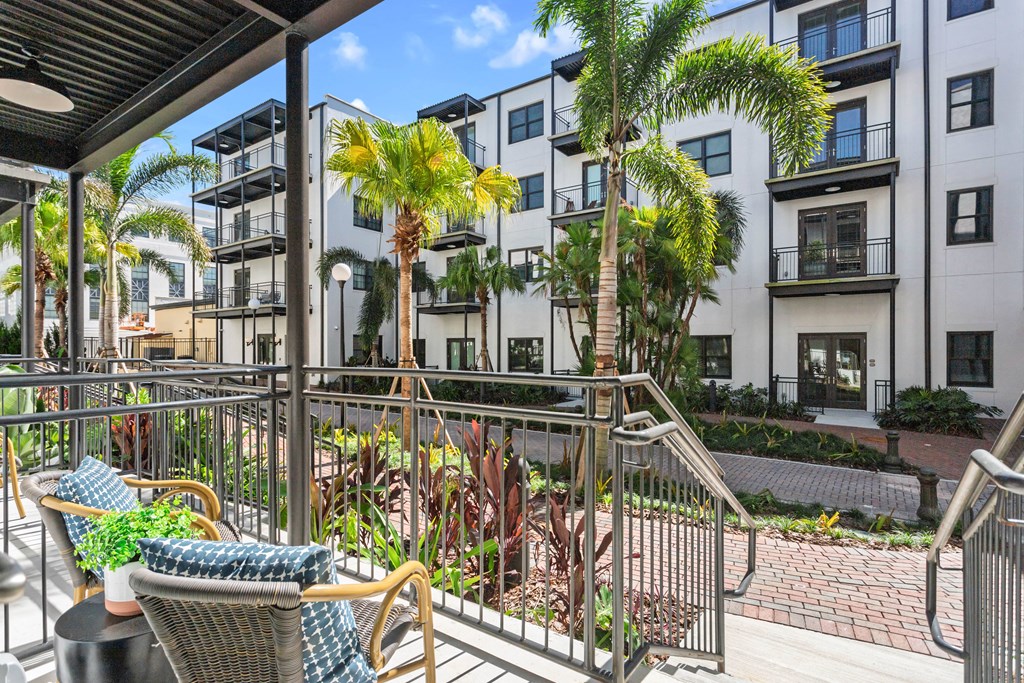 a balcony with chairs and palm trees in front of an apartment building at Casa Marti, Tampa, FL
