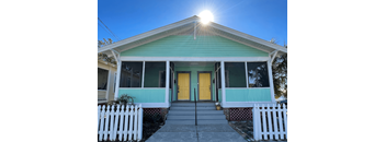 A house with a yellow door and a white picket fence.