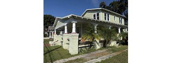 A white house with a green roof and a porch.