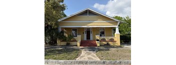 A yellow house with a red front door and steps.