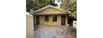 A yellow house with a brown door and windows.