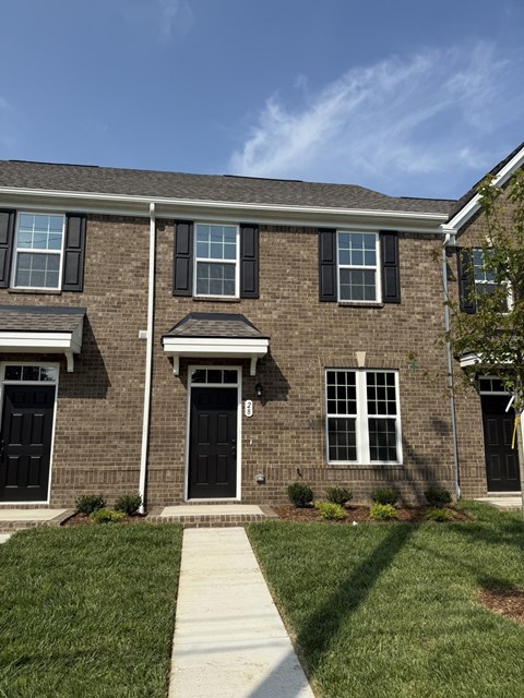 A brick house with a black front door and windows.