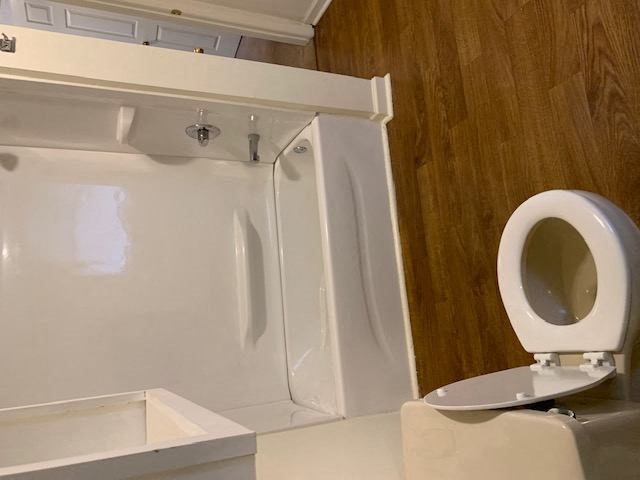 a white bathroom with wood style flooring at Hurd & Bone Property Management, Lebanon, Tennessee