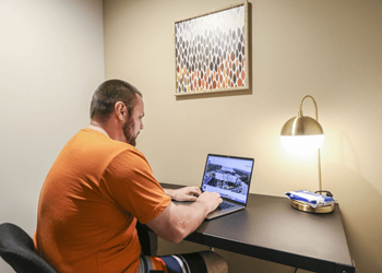 a man sitting at a desk using a laptop computer at Bluestone Lofts, Minnesota, 55803