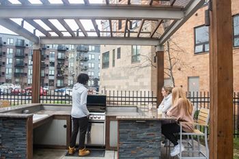 people sitting at a bar in a patio area with a grill at Bluestone Lofts, Duluth