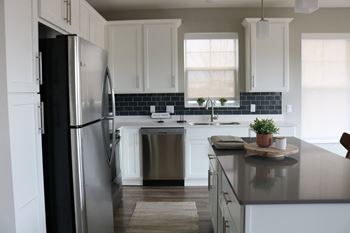 A kitchen with a black fridge and a black and white backsplash.