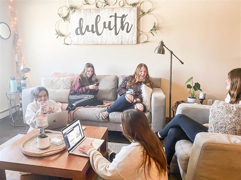 a group of women sitting on a couch in a living room with laptops