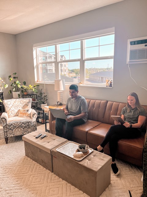 Two people sitting on a couch in a living room with a coffee table in front of them.