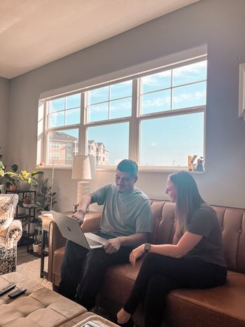 Two people sitting on a couch with a laptop.