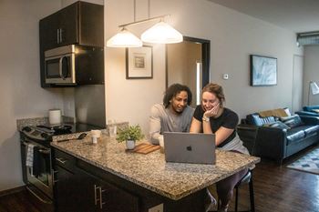 two women sitting at a kitchen counter looking at a laptop computer at Bluestone Lofts, Duluth, MN, 55803