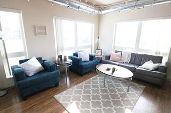 a living room with blue couches and a white rug at Bluestone Lofts, Duluth