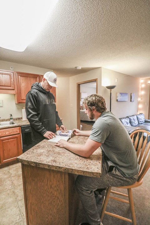 two men are sitting at a kitchen counter