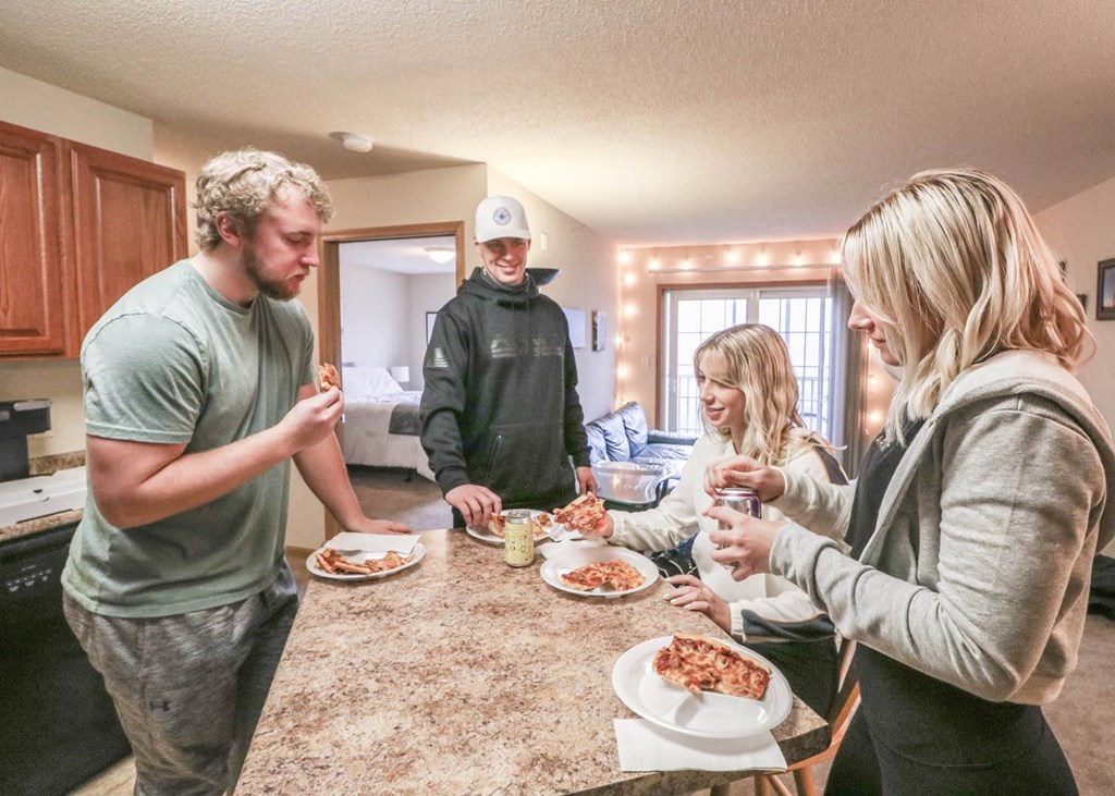 people gathered around a kitchen counter eating pizza at Boulder Ridge, Duluth Minnesota