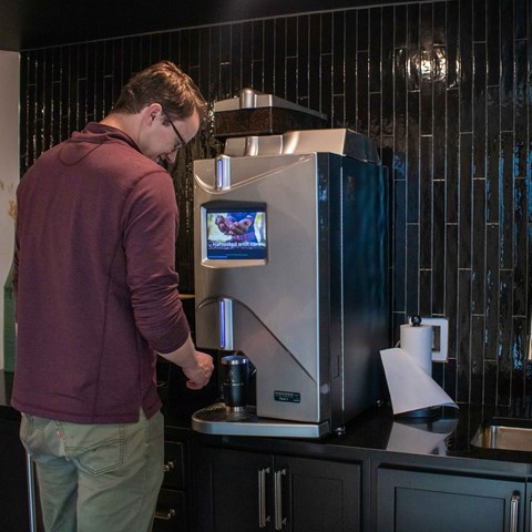 A man is using a coffee machine in a kitchen.