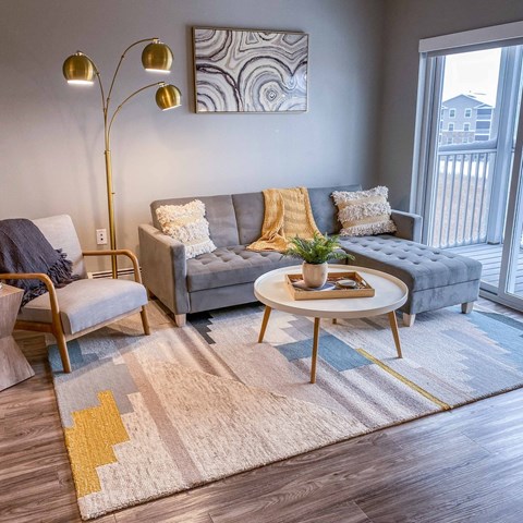 A living room with a grey couch, a wooden chair, a round coffee table, and a floor lamp.