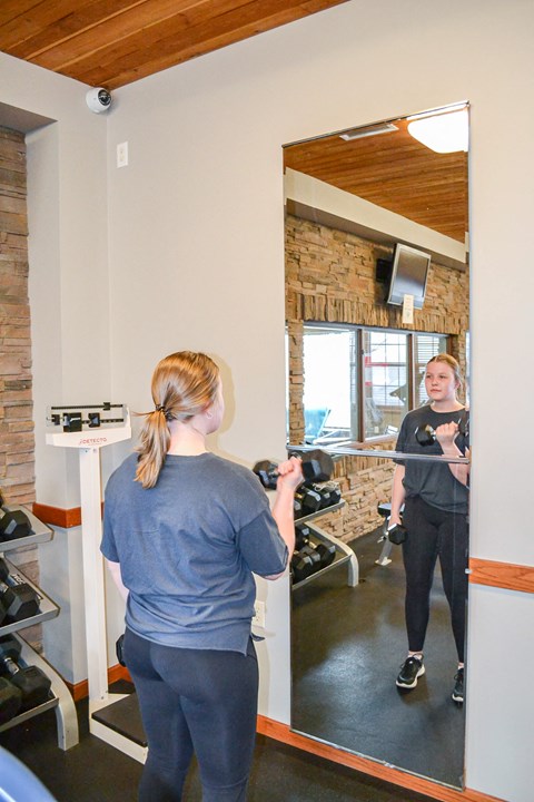 a woman taking a picture of herself in a mirror at a gym at Summit Ridge, Duluth