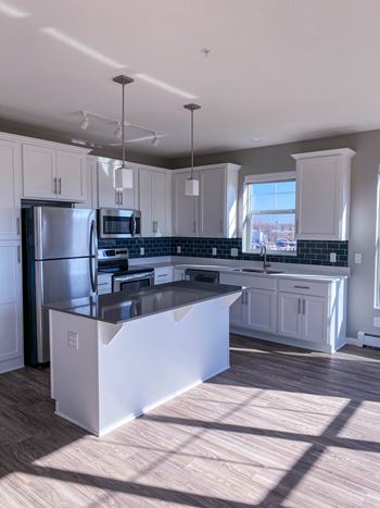 A kitchen with a refrigerator, microwave, and oven.