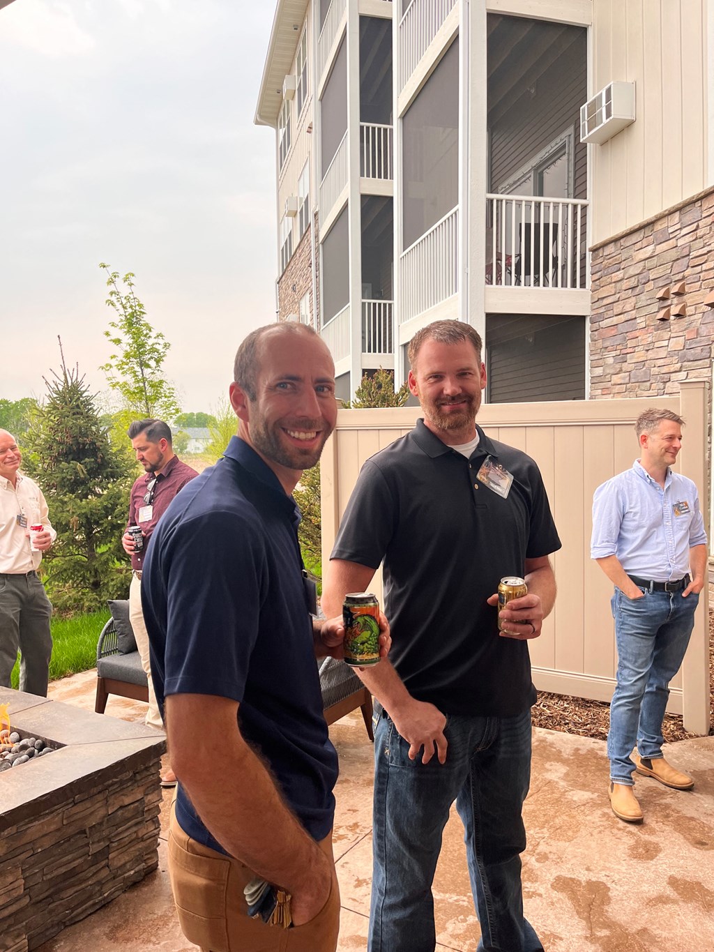 two men standing in front of a house holding beers  at Timber Ridge, Minnesota