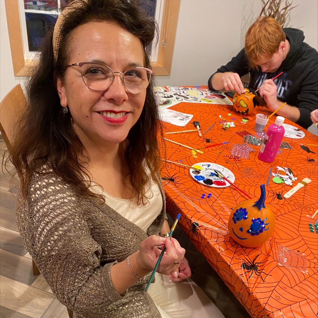 a woman is painting a pumpkin on a table with a boy  at Timber Ridge, Forest Lake, MN