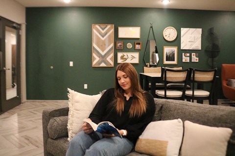 a woman sitting on a couch reading a book in a living room