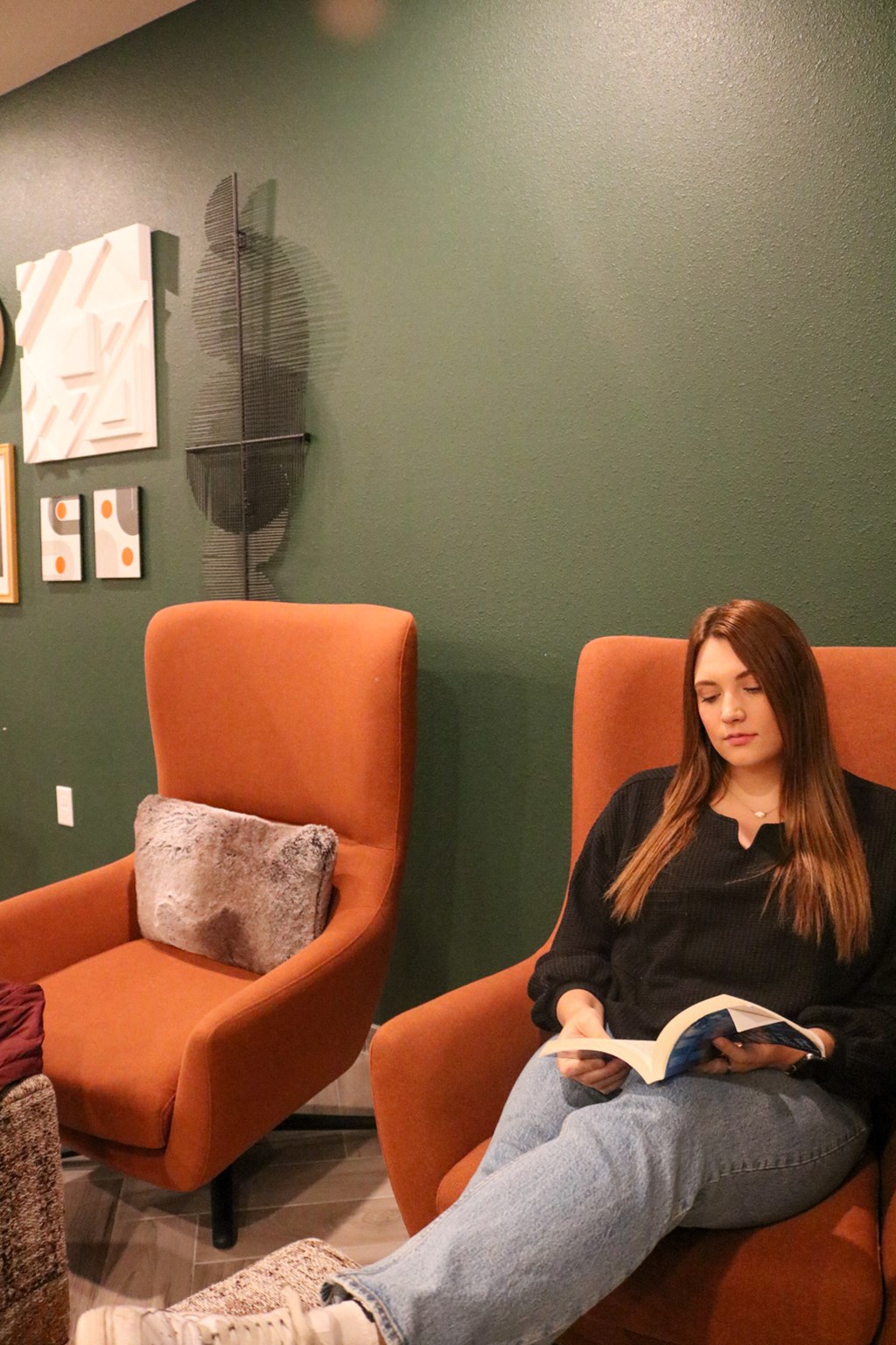 a woman sitting in a chair reading a book  at Timber Ridge, Forest Lake, MN, 55025