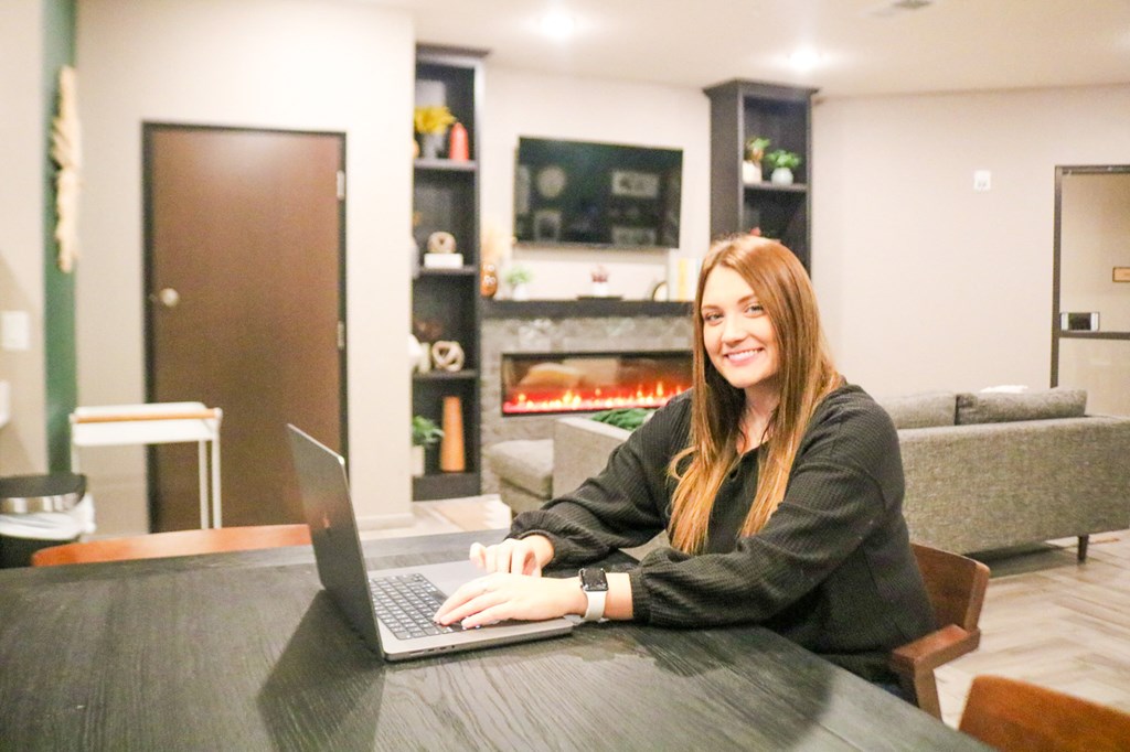 a woman sitting at a table with a laptop computer  at Timber Ridge, Forest Lake, MN, 55025