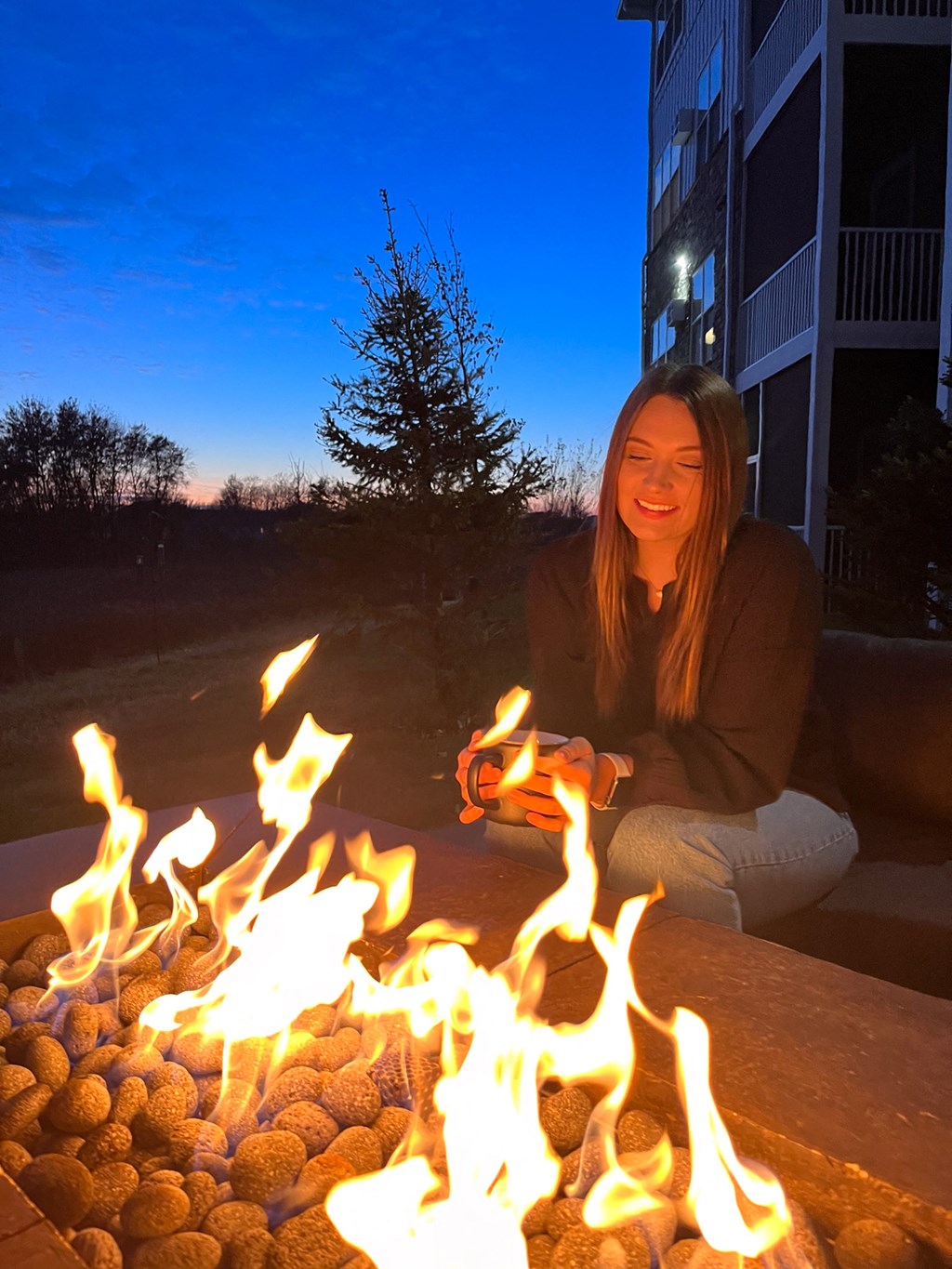 a woman sitting in front of a fire pit  at Timber Ridge, Minnesota