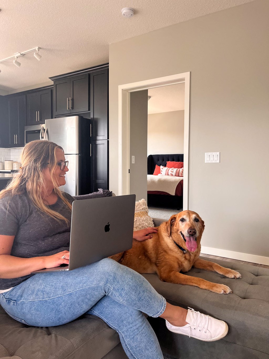 a woman sitting on a couch with her dog using a laptop  at Timber Ridge, Forest Lake