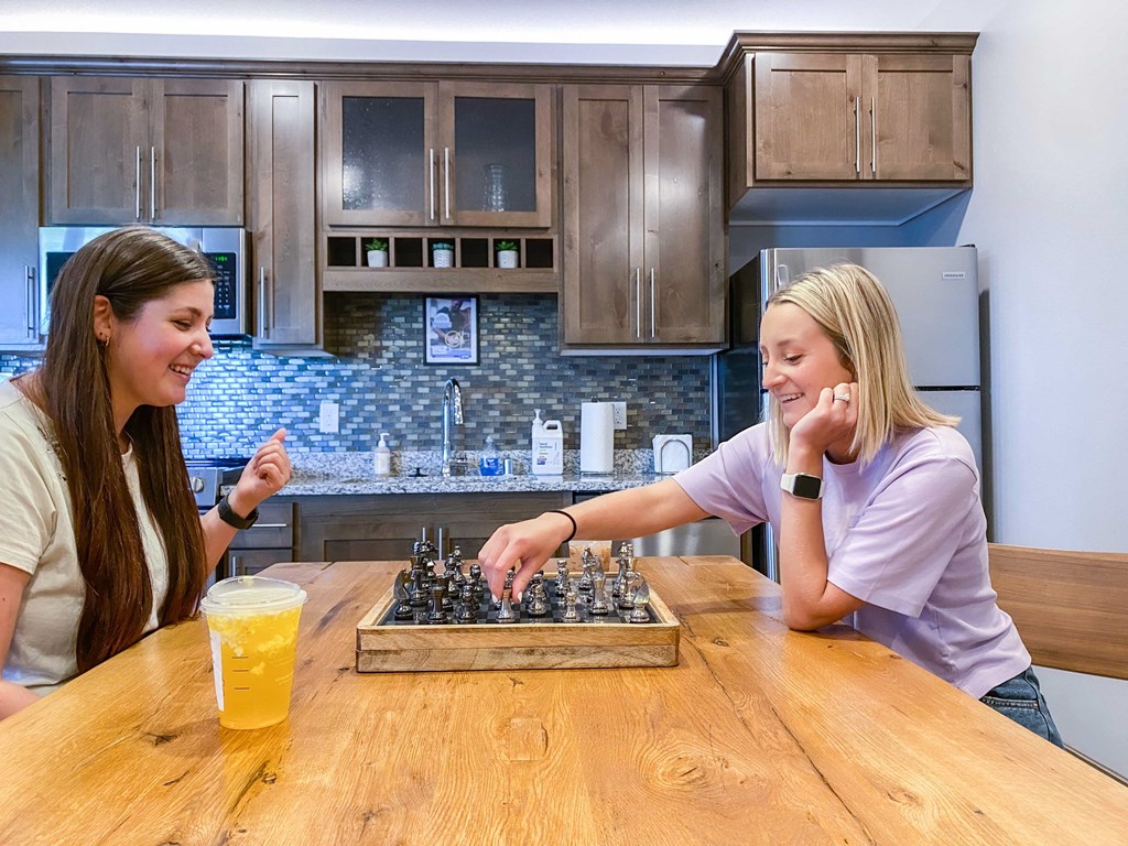 two girls playing chess at a kitchen table  at Timber Ridge, Forest Lake, MN, 55025