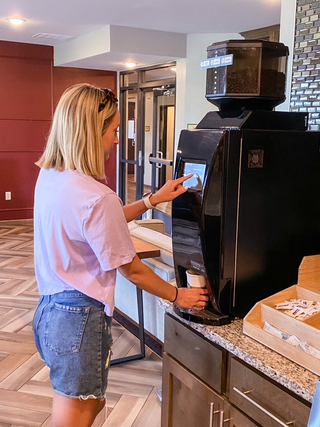 a woman putting a cup into an automatic coffee machine  at Timber Ridge, Forest Lake