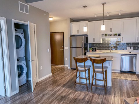 an open kitchen and dining area with white cabinets and wood floors