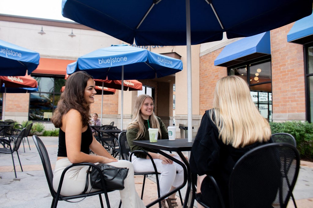 three women sitting at a table under an umbrella at Bluestone Lofts, Minnesota, 55803