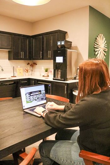 A woman is sitting at a table using a laptop.
