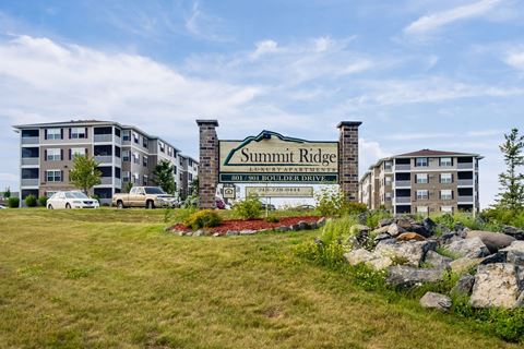 a sign for summit apartments with buildings in the background