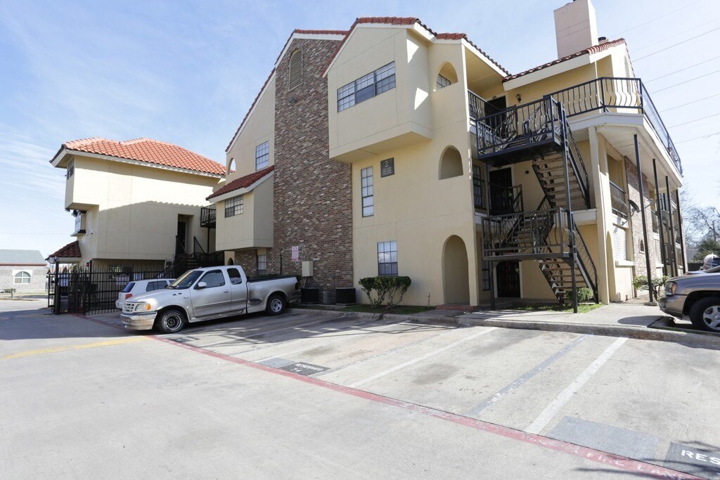 A silver truck is parked in front of a two-story building.