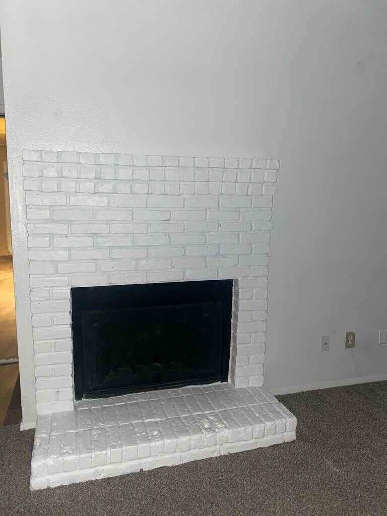 A white brick fireplace with a black firebox.