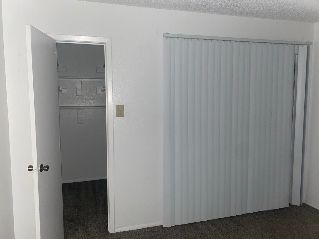 A white door with a black handle is open to a room with a white wall and a grey curtain.