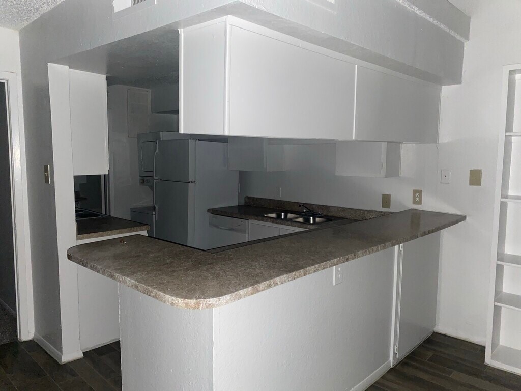 A kitchen with white cabinets and a granite countertop.