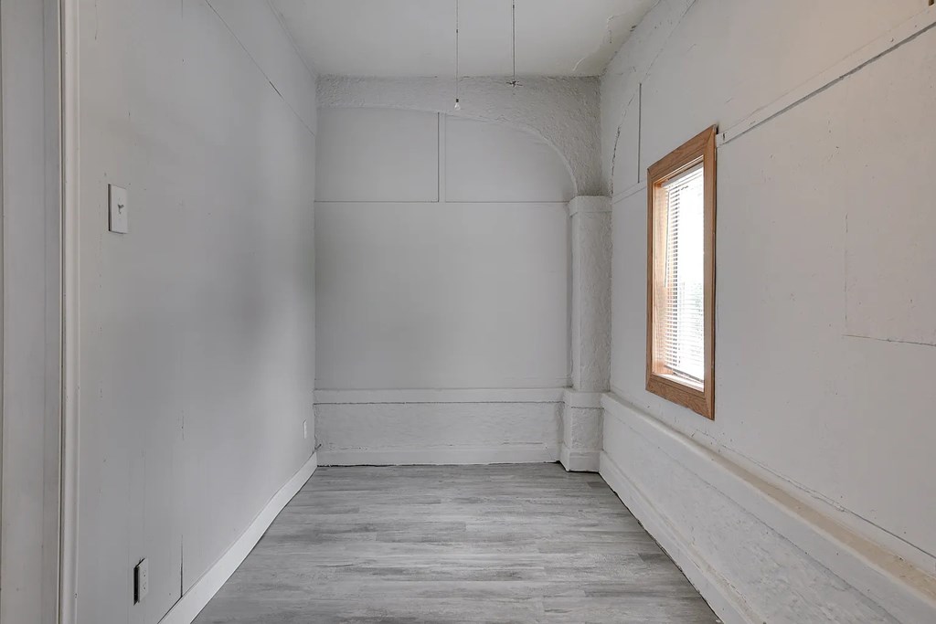 A room with a window and wooden flooring.
