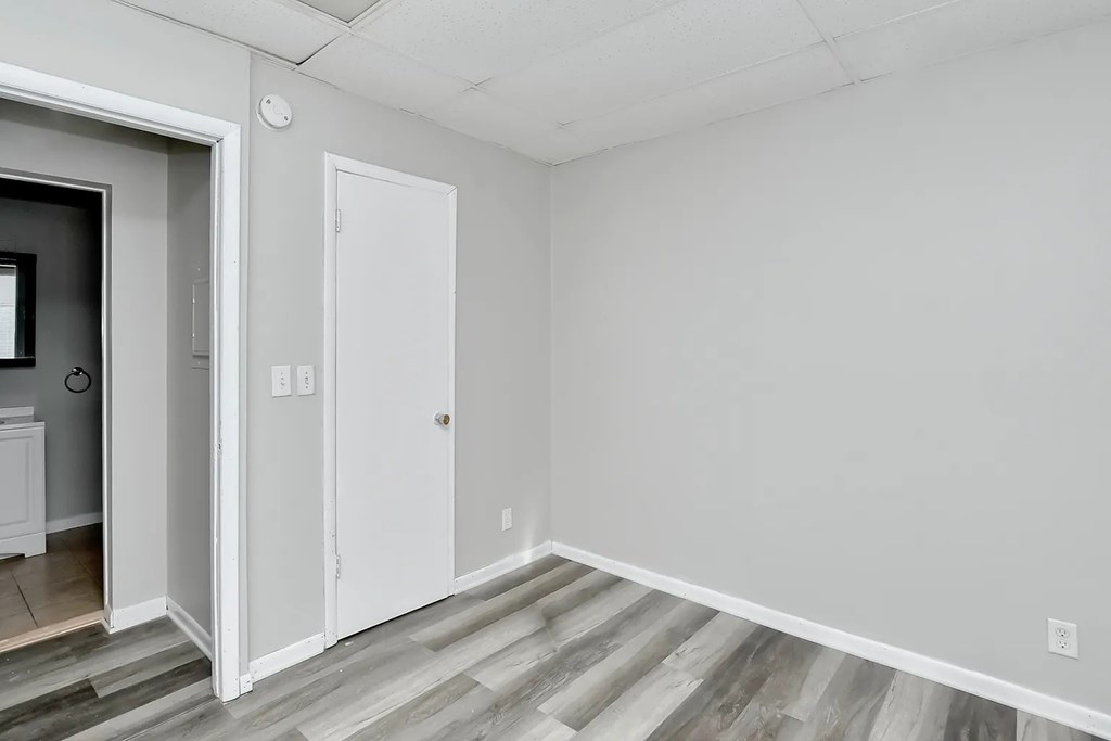 A room with a white door and a grey floor.