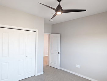 A room with a ceiling fan and two doors.