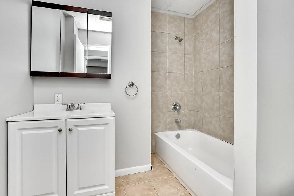 A white bathroom with a tub, sink, and mirror.