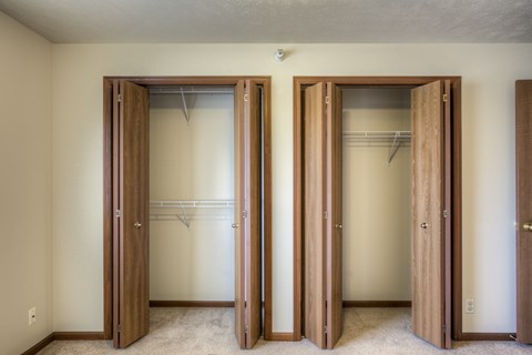 Three wooden closet doors are open in a room.