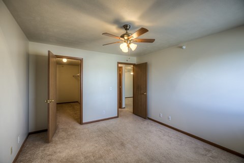A room with a ceiling fan and carpeted floor.