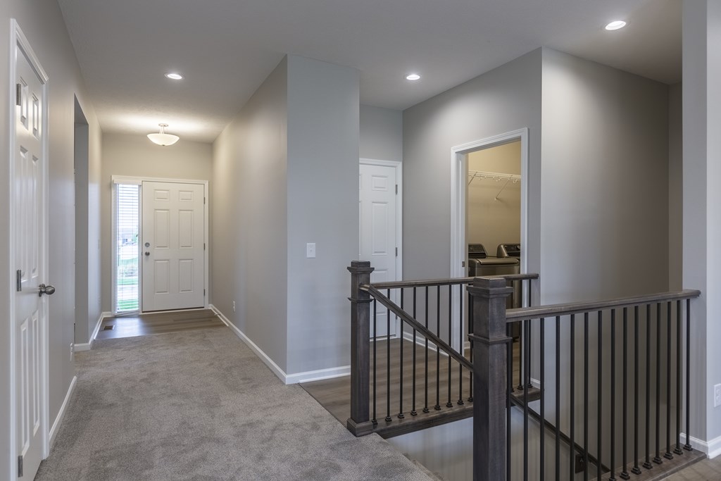 A hallway with a black railing and a white door.